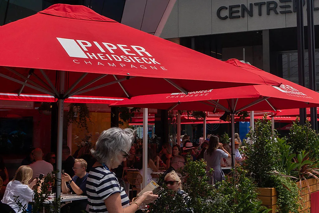A collection of red branded parasols with logo printing covering an restaurant outdoor dining space.